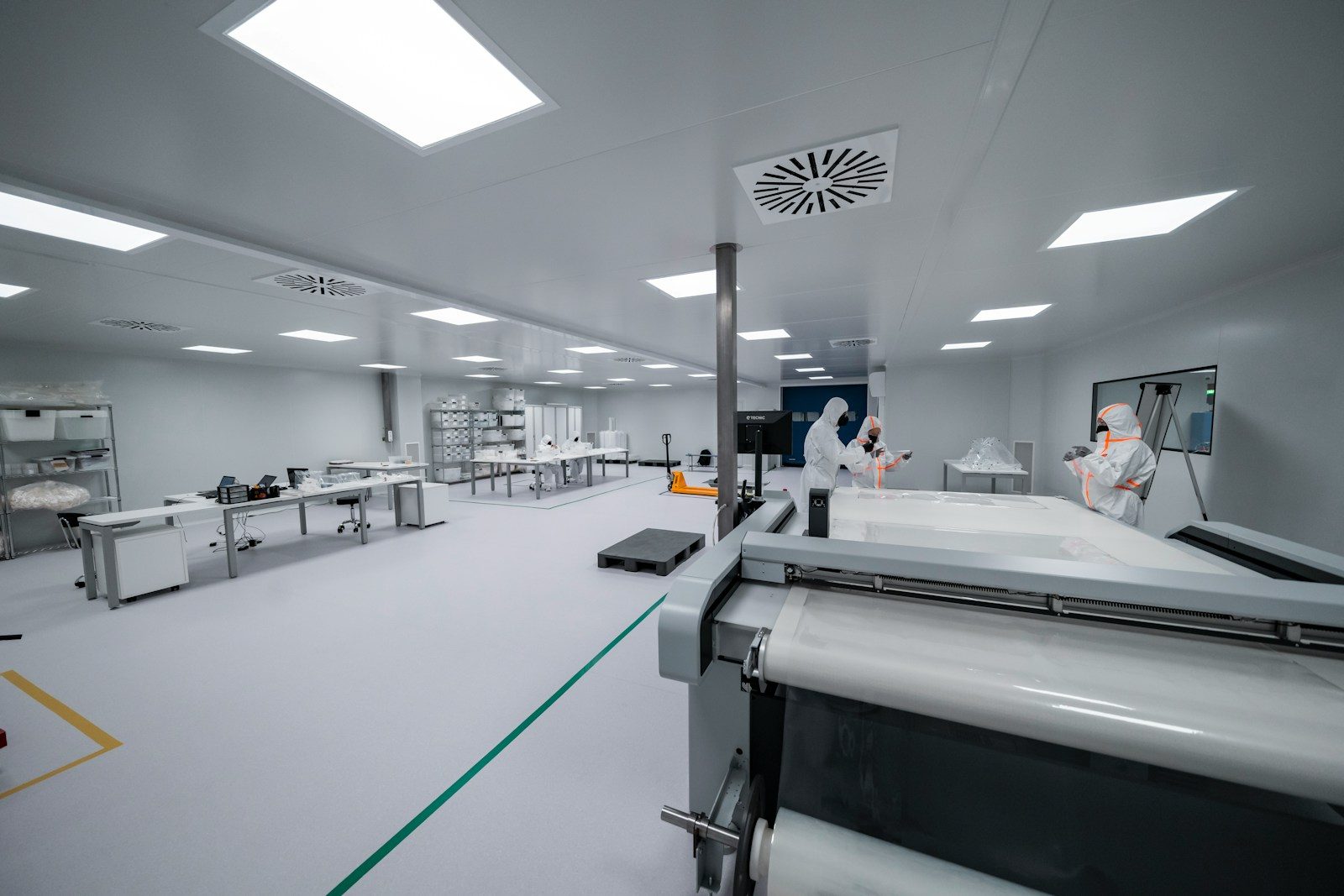 Workers are inside a clean room manufacturing something