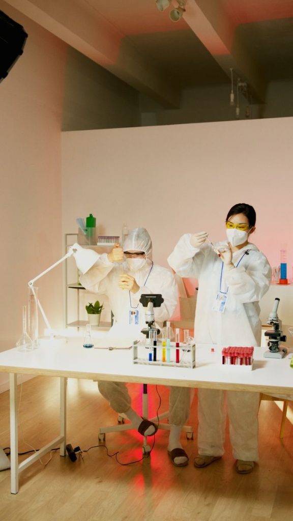 Lab staff in protective gear working with sample tubes