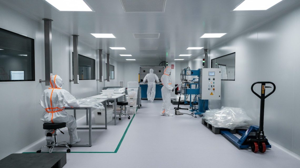 Workers in protective suits inside a sterile laboratory