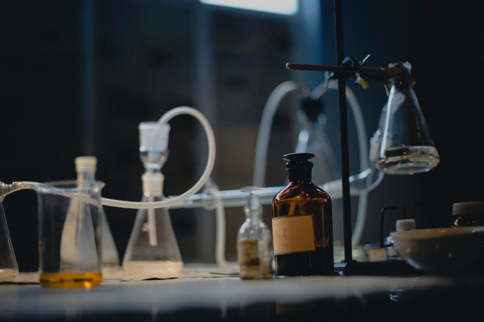 Laboratory glassware sits on a dark, illuminated table