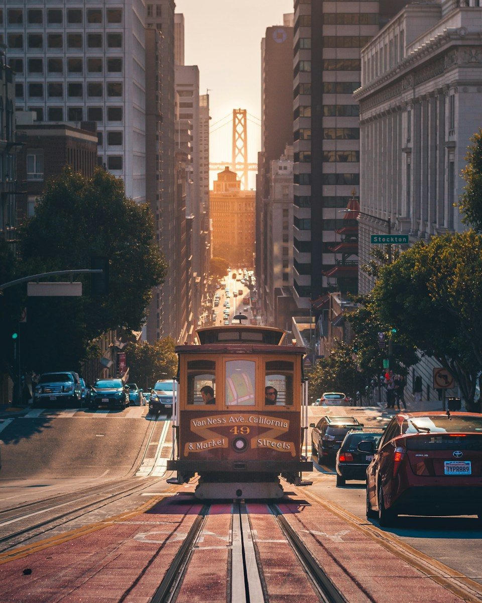 A cable car on tracks in San Francisco with the Bay Bridge in distance