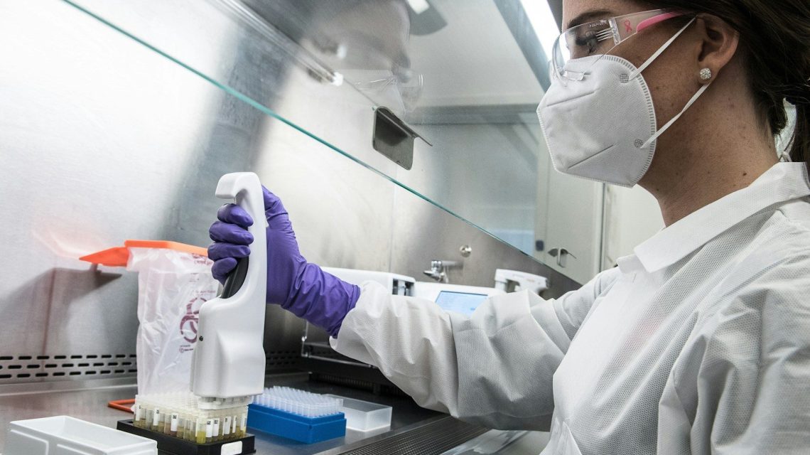 person in white gloves holding purple plastic bottle