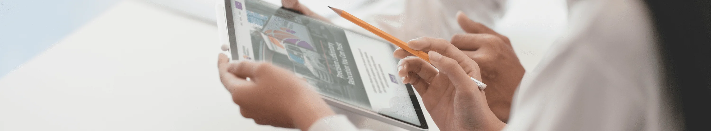 Closeup of hands using iPad and pointing to screen with pencil