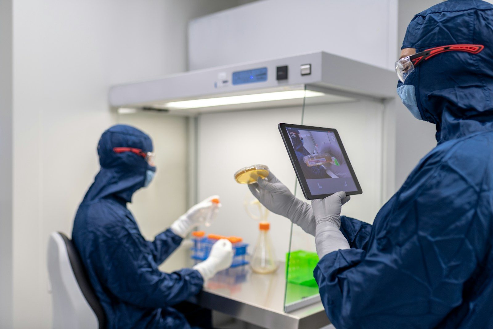 Researchers in cleanroom gowns working at a biosafety cabinet