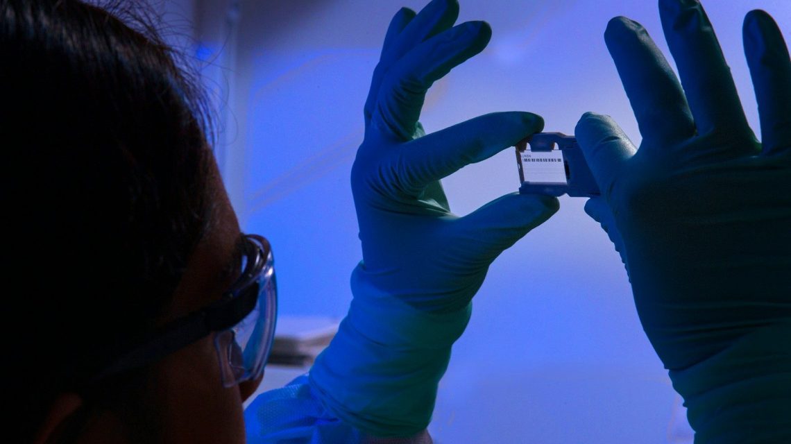a person wearing gloves and holding up a cell phone