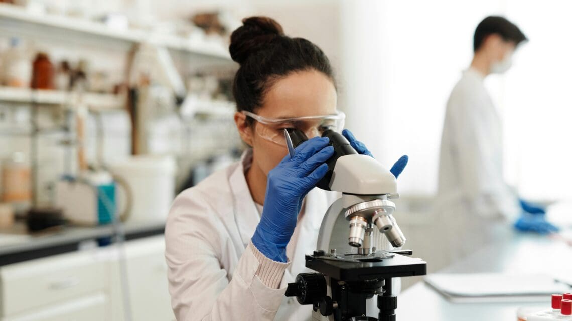 Woman looking through microscope in a lab