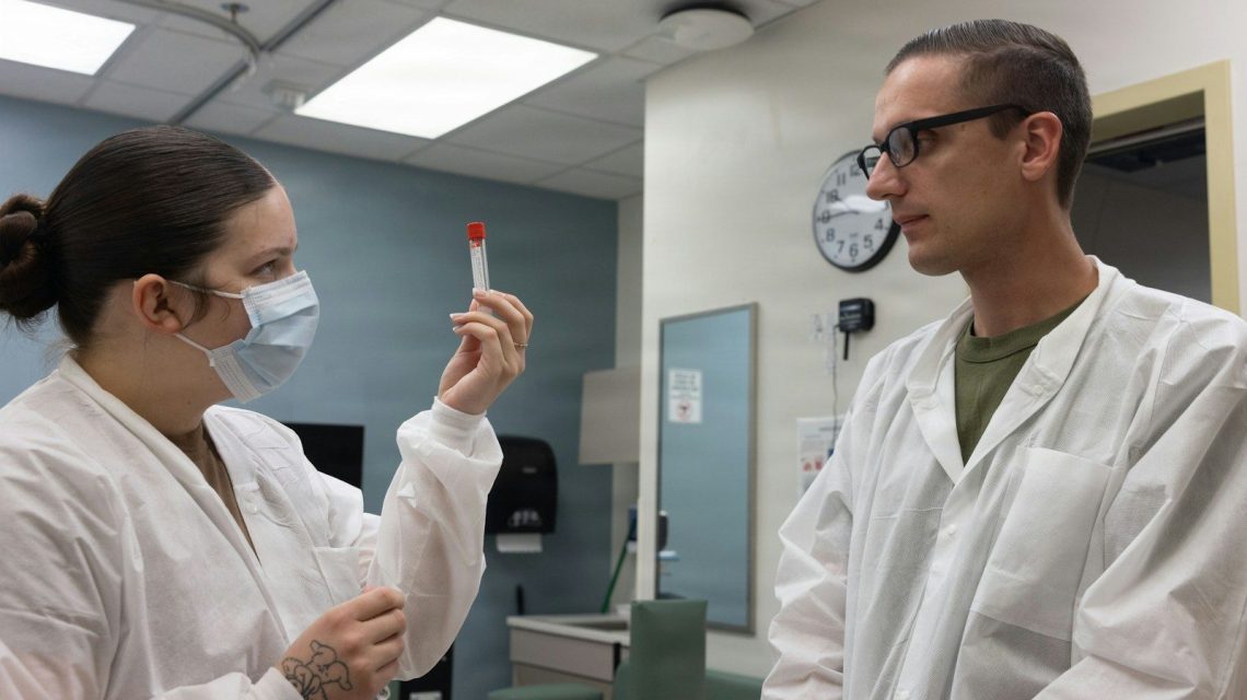 Two medical professionals in lab coats examine a test tube