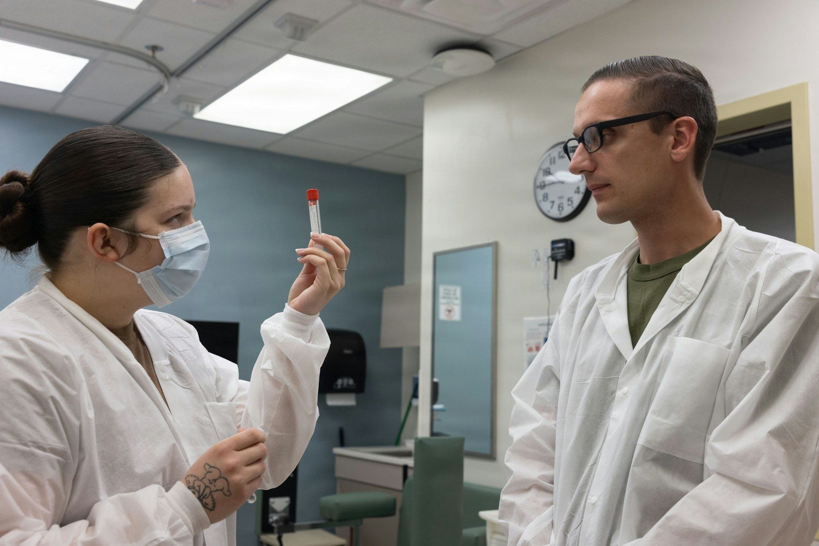 Two medical professionals in lab coats examine a test tube