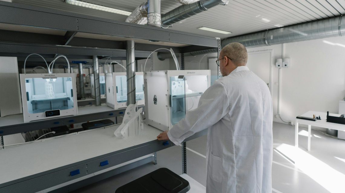 man in white laboratory gown standing near white and black machine
