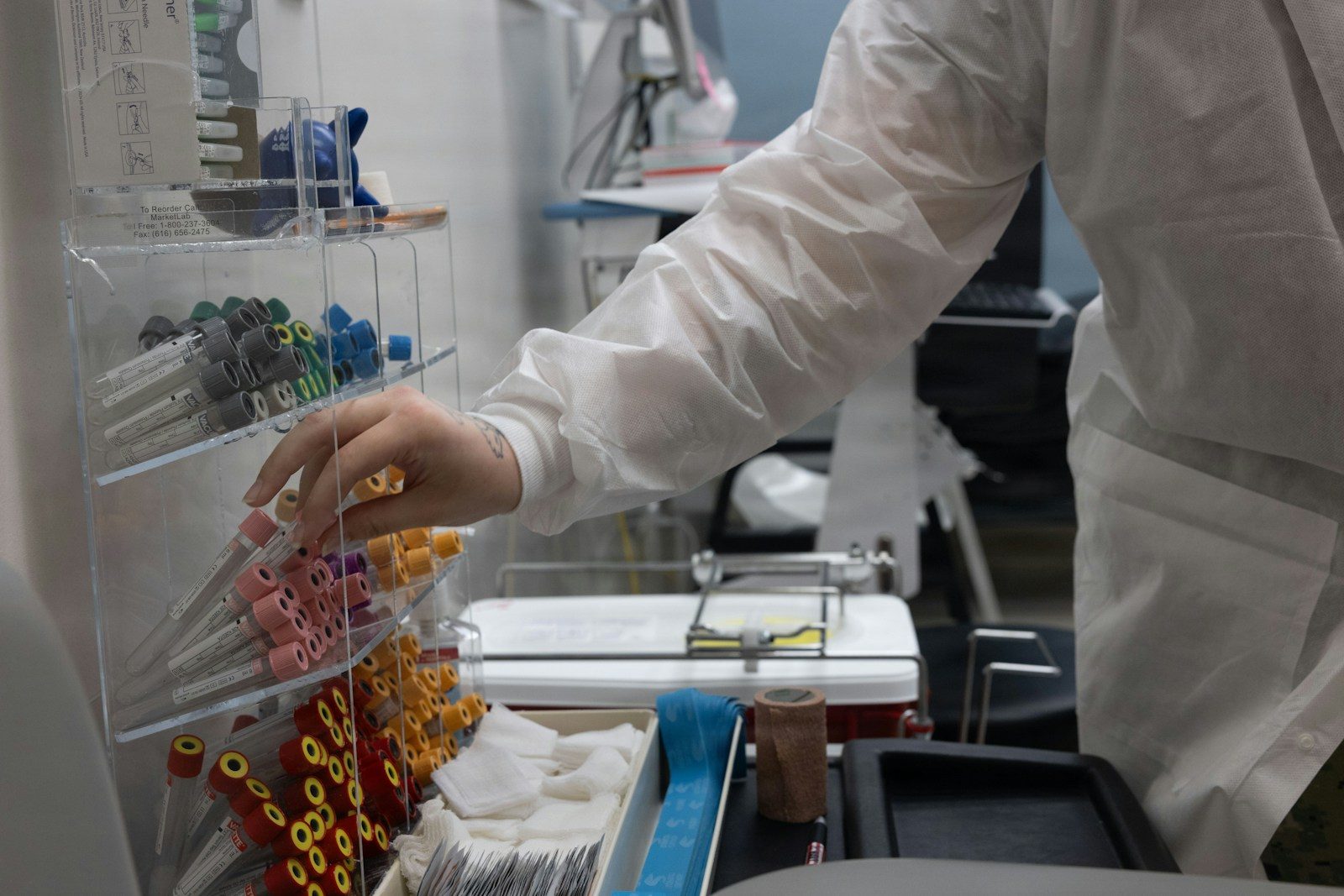 Person in lab coat selecting supplies from rack